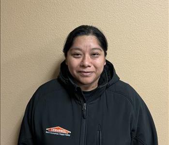 Image of a woman standing in front of a wall in SERVPRO apparel.